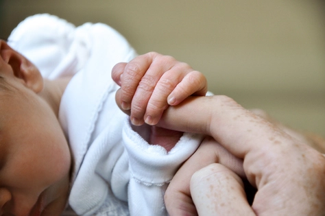 Малыш держится за палец